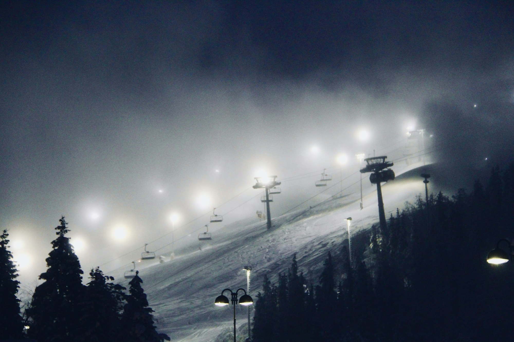 Levi ski slope glowing under lights on a misty winter night