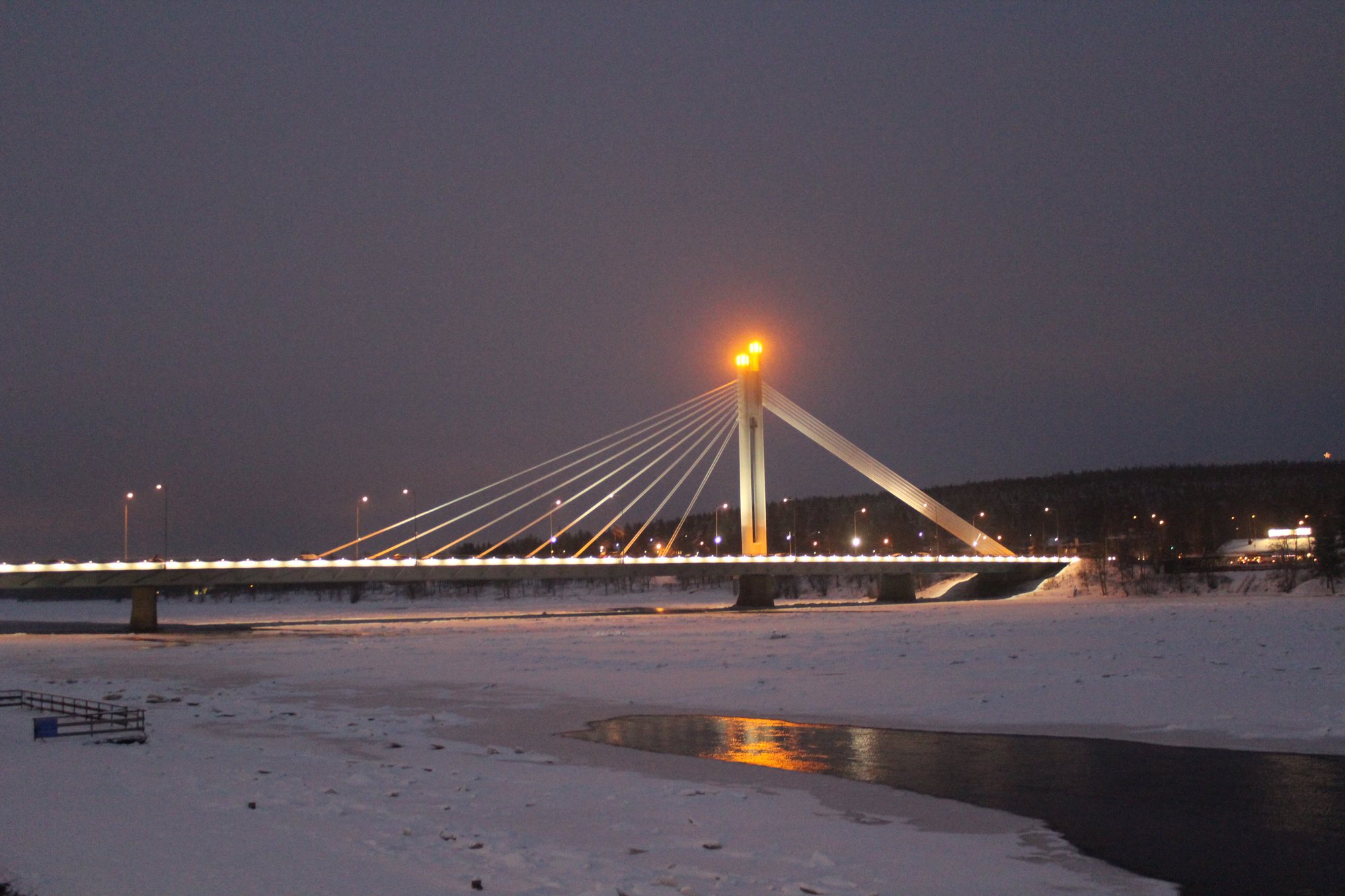 The illuminated Lumberjack’s Candle Bridge over a frozen river in Rovaniemi.